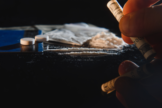 Purchase, possession and sale of drugs is punishable by law. Many types of narcotics and drugs represented on table.