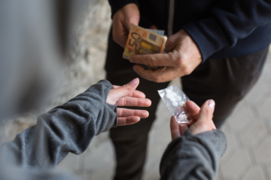 drug trafficking, crime, addiction and sale concept - close up of addict with money buying dose from dealer on street