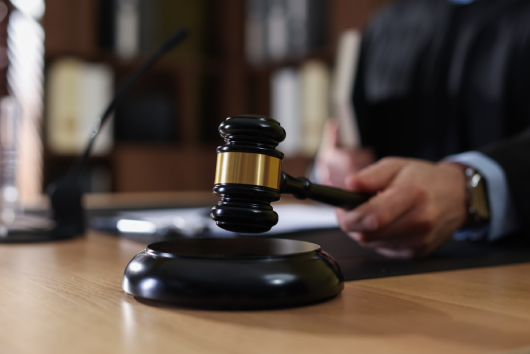 Judge striking gavel at wooden table indoors, selective focus