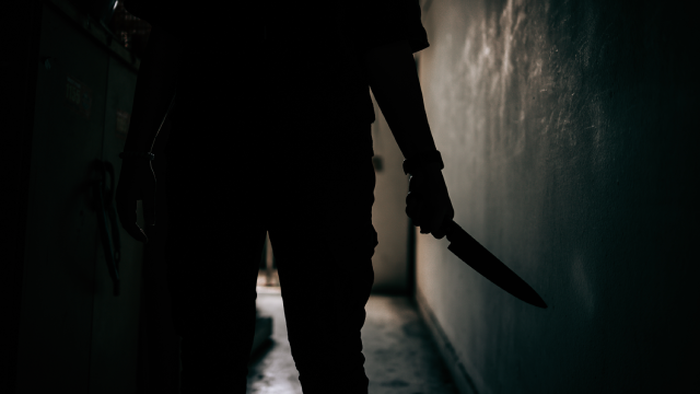 The shadow of a female murderer stood terrifyingly holding a knife and lit from behind.Scary horror or thriller movie mood or nightmare at night Murder or homicide concept.