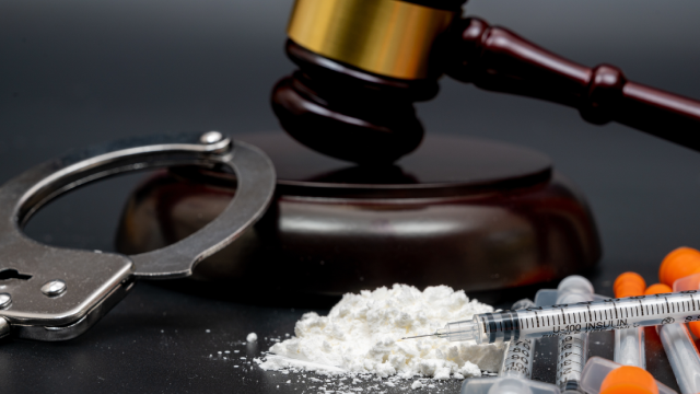 Drug crime concept with white powder and disposable syringe on black background