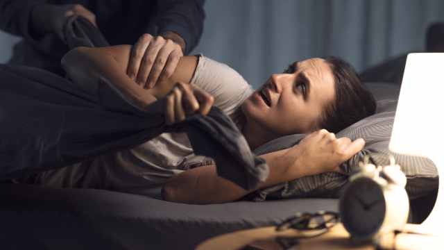 Aggressive man attacking his wife lying in bed, domestic violence concept